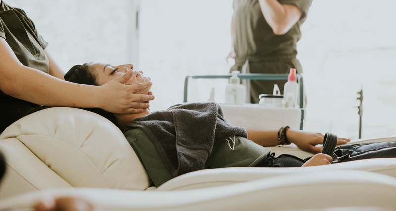 Woman applying aromatherapy-infused facial oil in soft natural light with eucalyptus and lavender sprigs nearby